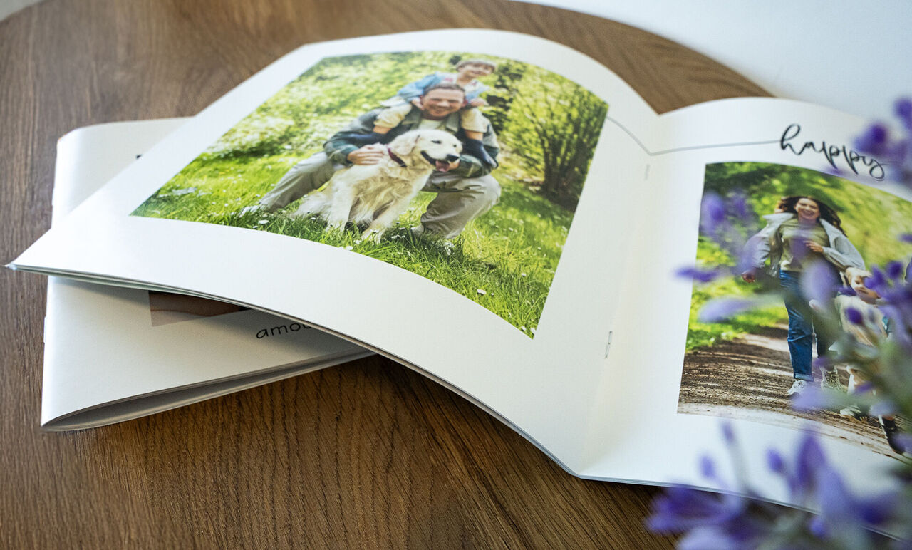 Un album photo ouvert avec des photos d'une famille en plein air. À gauche, un homme avec un chien et ses enfants. À droite, une femme avec ses enfants en promenade.