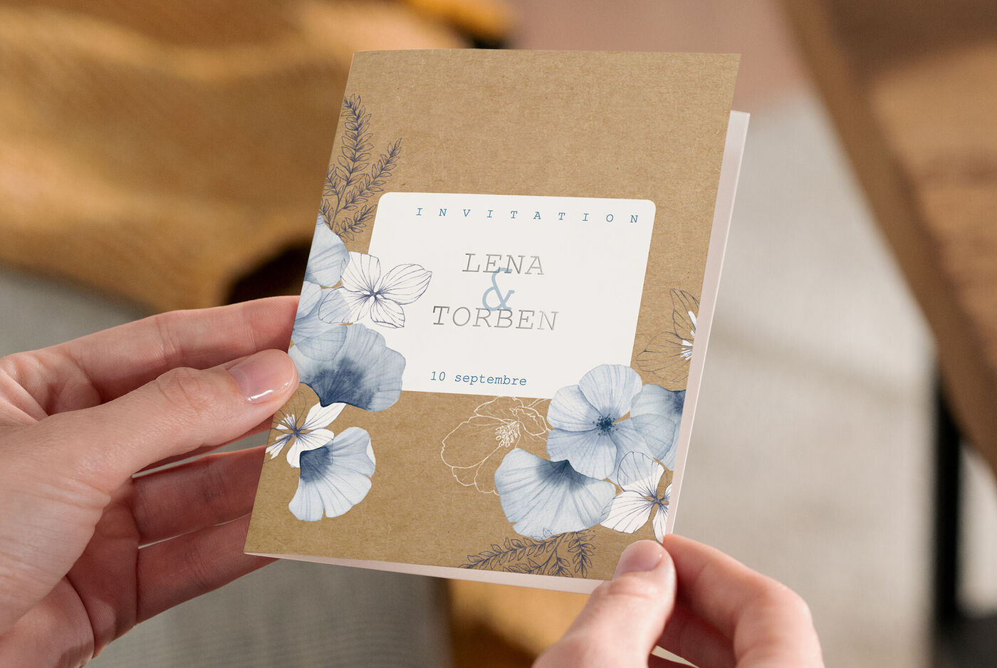 Une magnifique carte d'invitation aux couleurs douces avec un motif floral. Sur le devant se trouvent « Invitation » et les noms « Lena & Torben ».