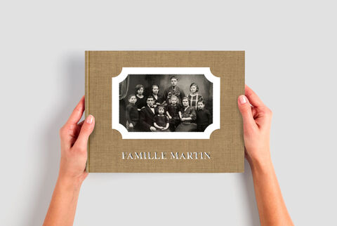Une main tient un album photo CEWE avec le titre 'Famille Martin' et une photo en noir et blanc.