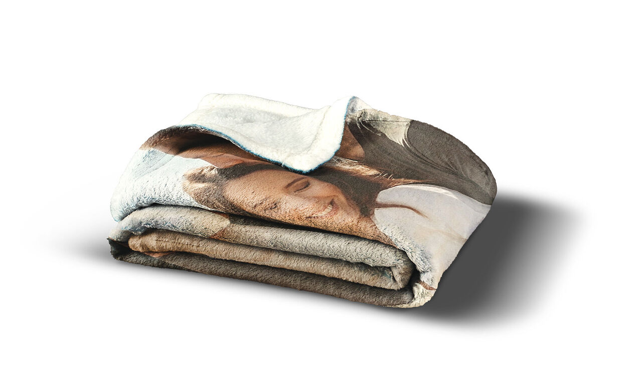 Une couverture pliée et personnalisée avec un sourire. La couverture montre une femme heureuse avec de longs cheveux et une expression aimante. Parfaite pour des moments confortables.