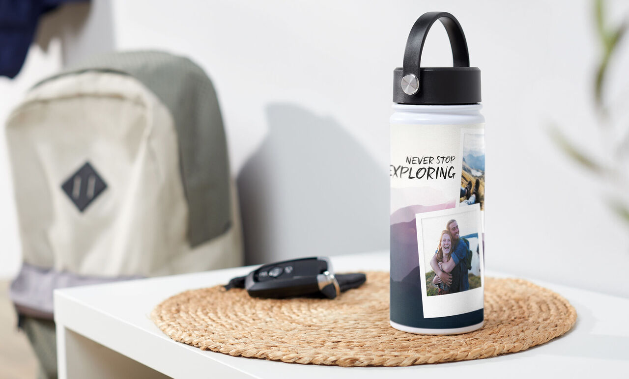 Bouteille d'eau avec le texte « Never Stop Exploring » et des photos sur une table.
