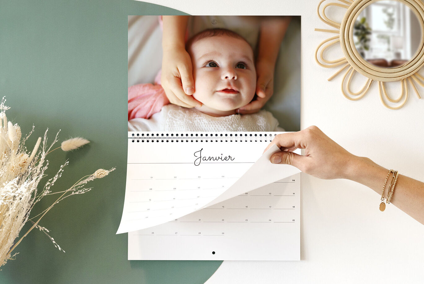 Des mains feuillettent un calendrier photo CEWE pour janvier.