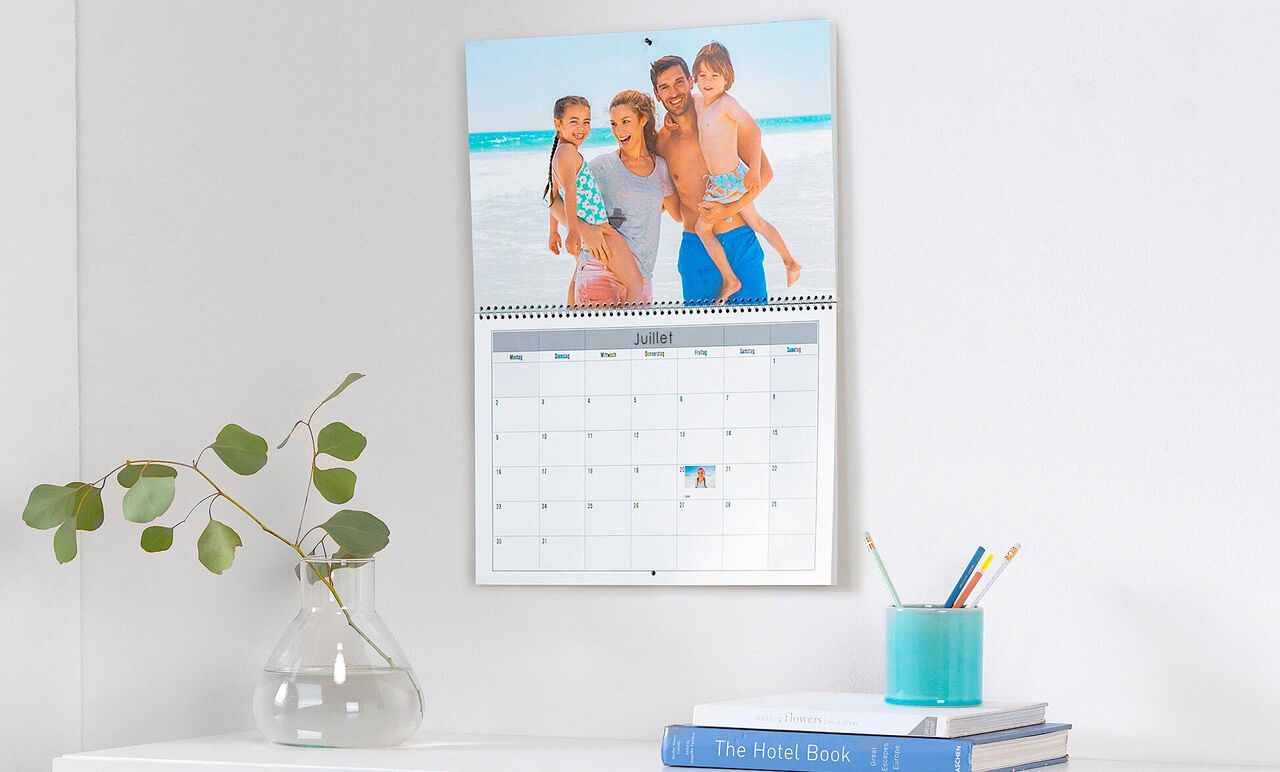 Une famille pose joyeusement devant un calendrier avec une photo d'été.