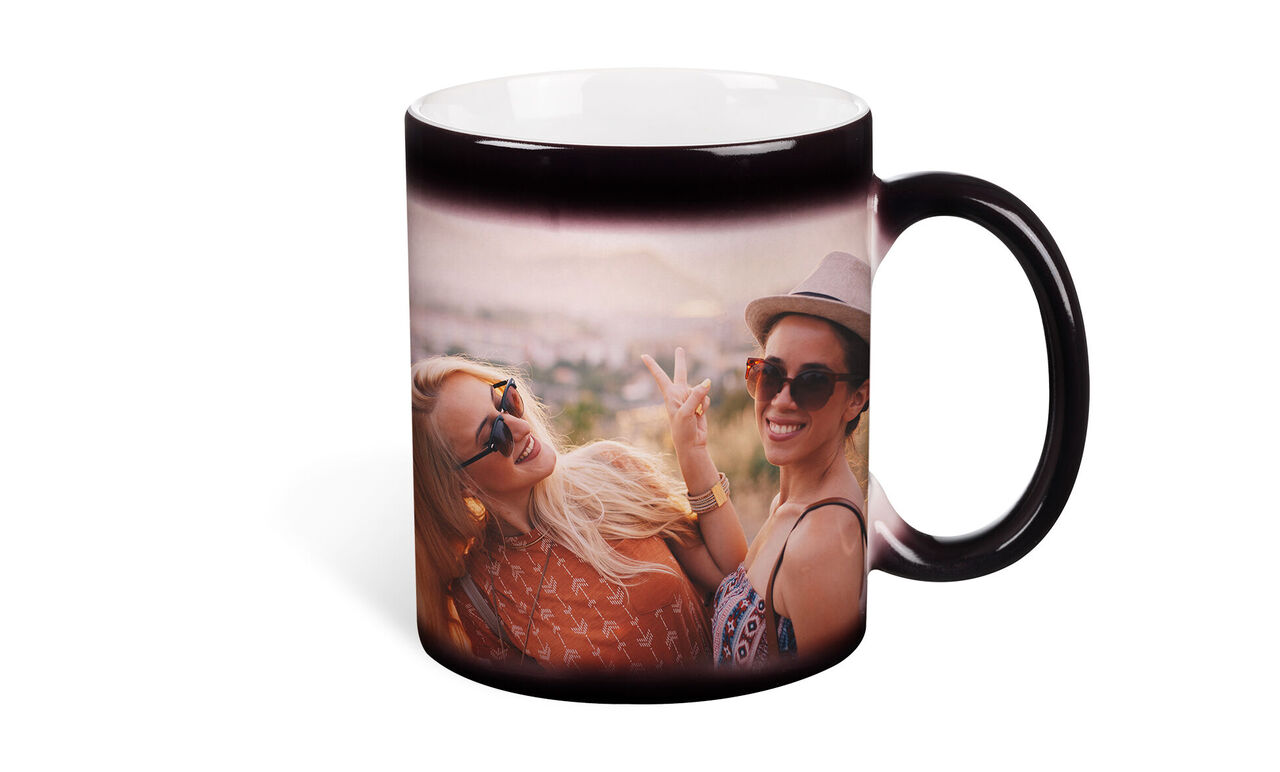Deux femmes sourient et posent joyeusement avec des lunettes de soleil dans un endroit pittoresque, l'une tient une tasse.