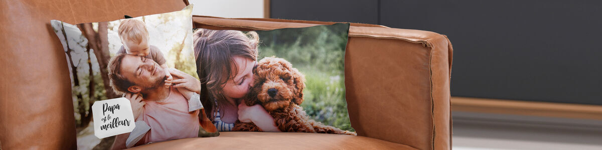 Deux coussins avec photos de famille sur un canapé. L'un montre un père avec un enfant, l'autre une femme étreignant un chien.