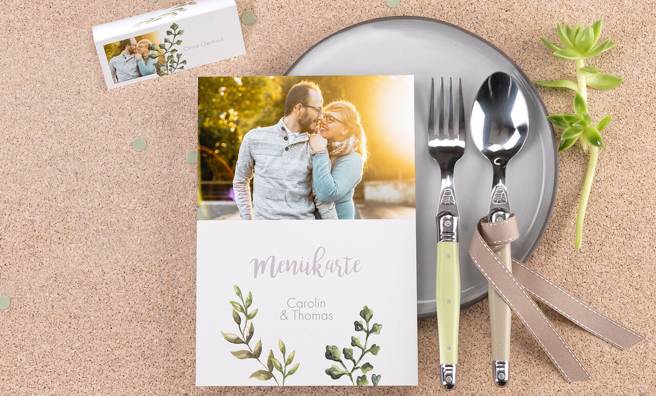 Une table magnifiquement dressée avec un menu montrant des noms et un design floral