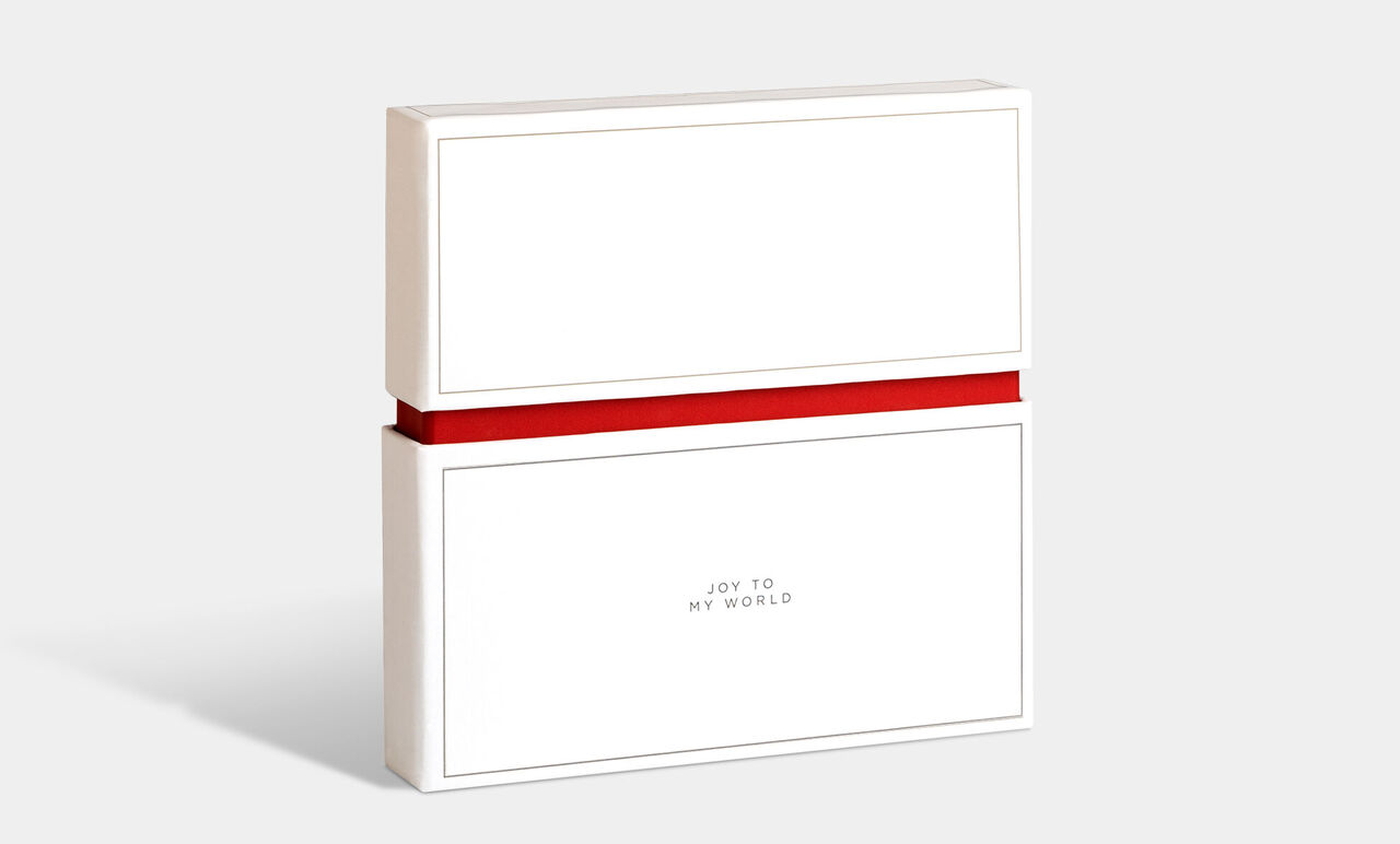 Emballage cadeau blanc avec un ruban rouge, étiqueté 'Joy to my world'