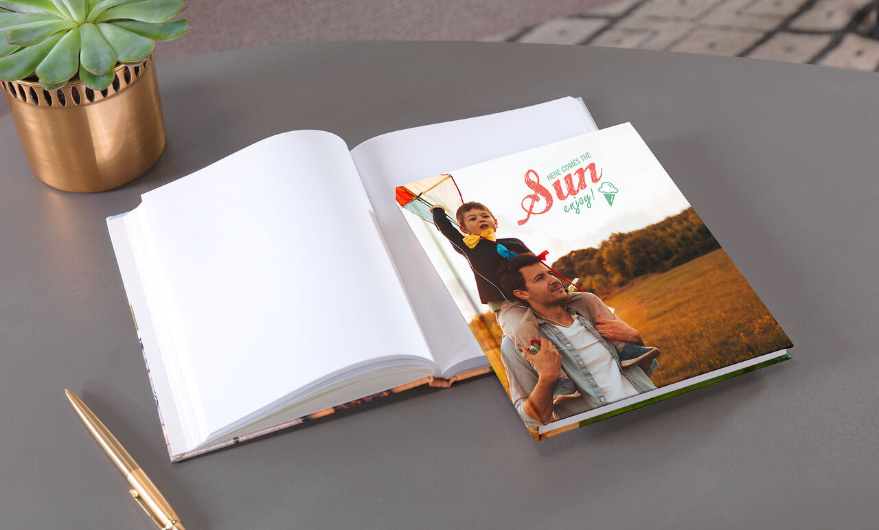 Un père porte son fils sur ses épaules devant un livre photo aux pages ouvertes.