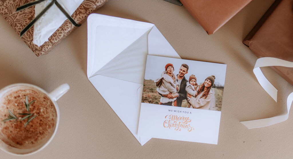 Une famille joyeuse pose pour une photo de Noël avec une enveloppe ouverte et des cadeaux en arrière-plan.
