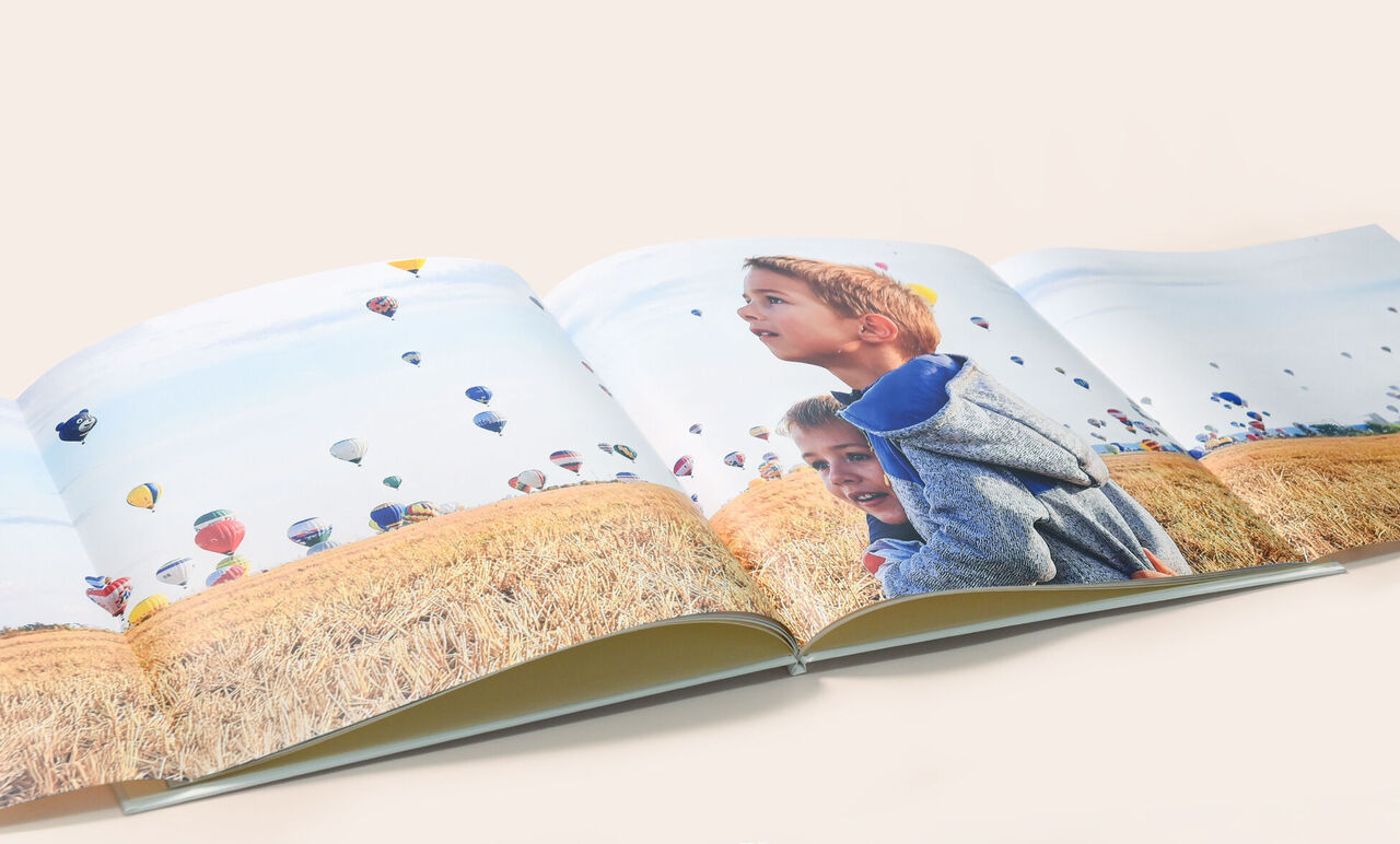 Un livre photo ouvert avec des montgolfières colorées au-dessus d'un champ de blé.