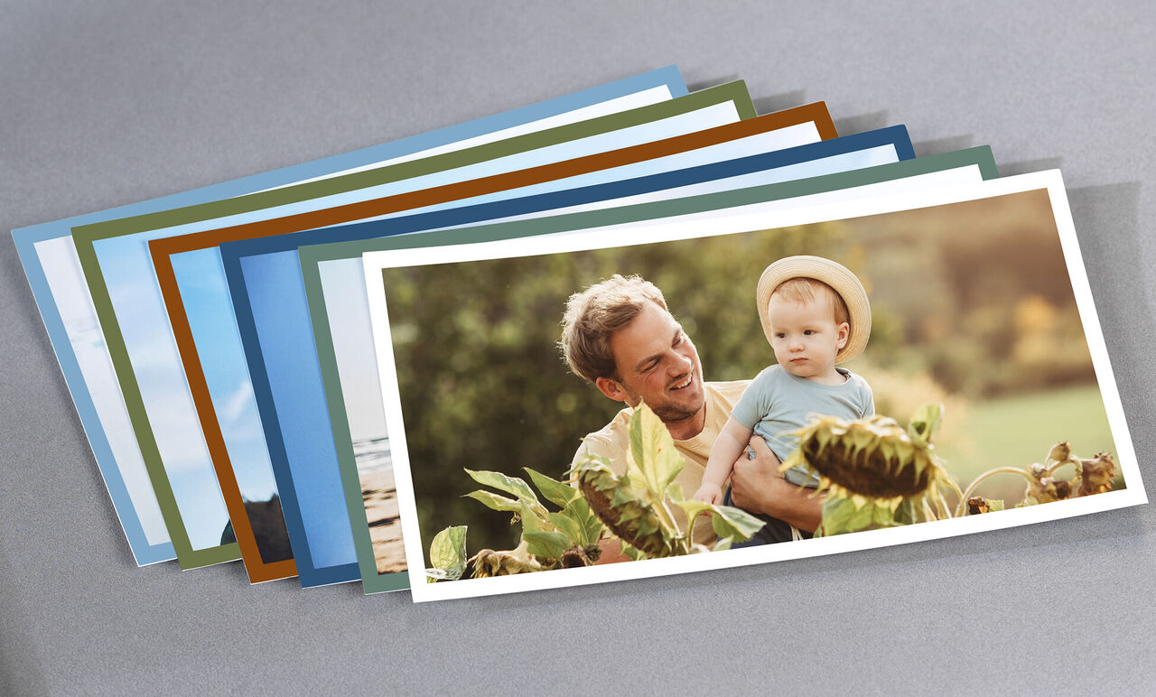 Un homme joyeux tient un enfant dans la nature et sourit. Entouré de pages colorées de livre photo, c'est un moment heureux.