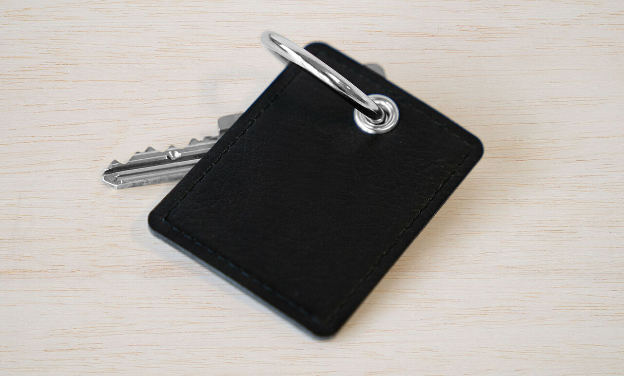 Un trousseau de clés avec un porte-clés noir sur fond de bois clair.