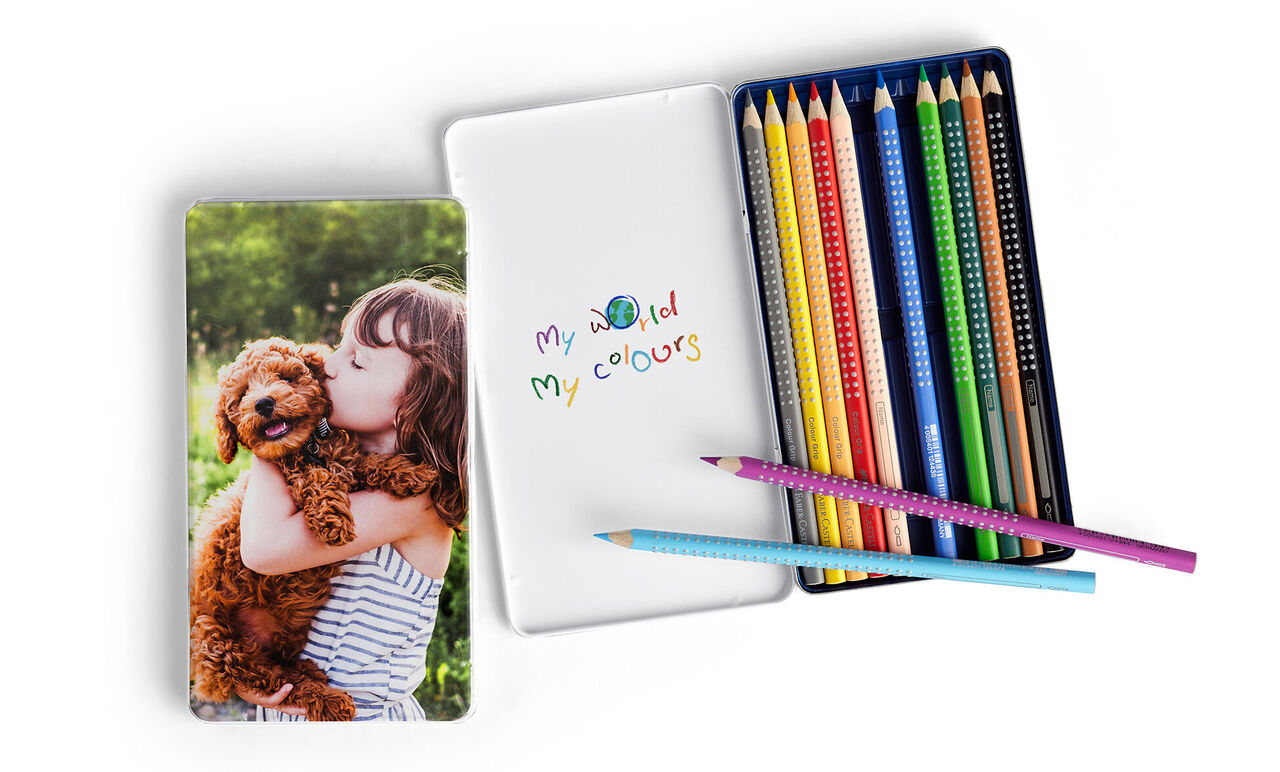 Un enfant joyeux étreint un chien sur un carnet. Des crayons colorés à côté.