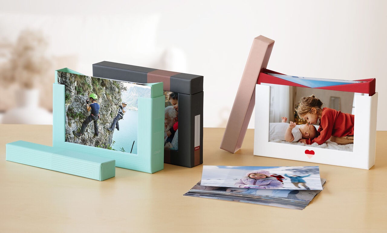 Deux CEWE Photo Books sur une table. Un montre un enfant étreignant un parent, l'autre un alpiniste.