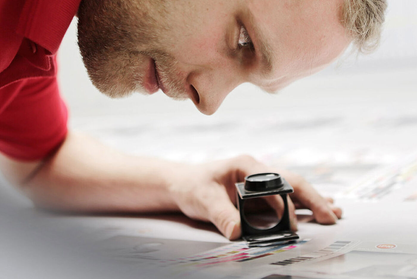 Une personne examine des motifs imprimés sur une table avec une loupe.