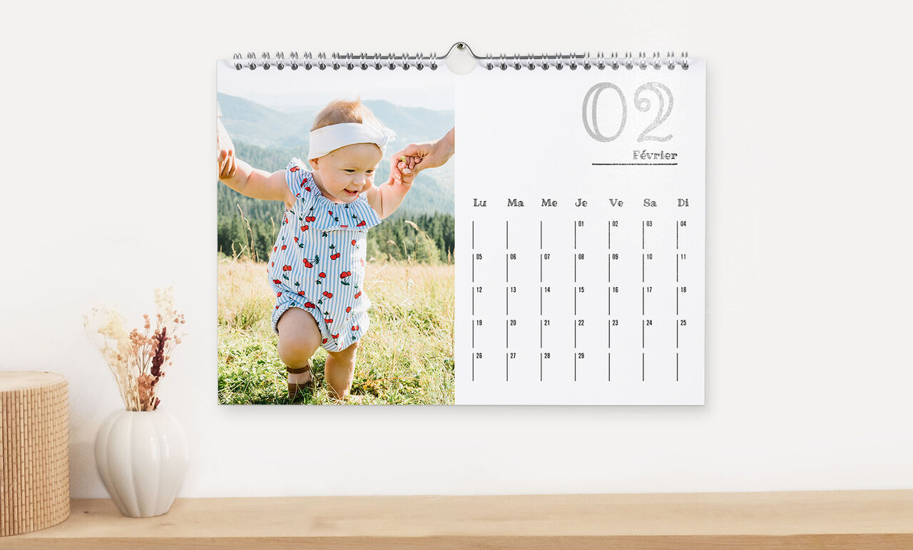 Un enfant dans une tenue colorée explore un champ de fleurs, tenu par la main. Douces collines en arrière-plan.