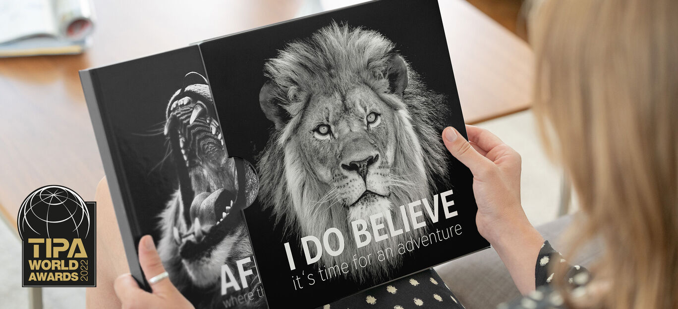 Personne tenant un album photo avec un lion sur la couverture.