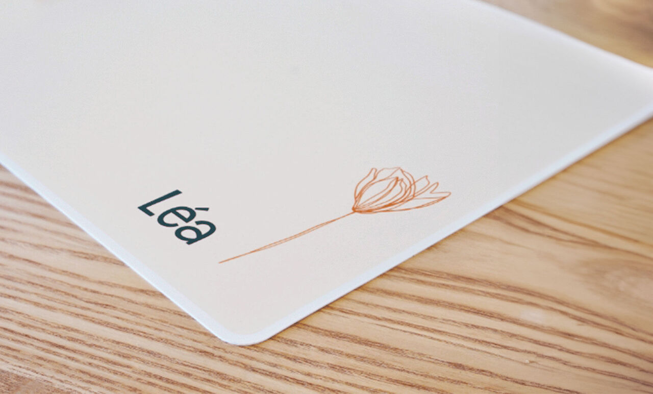 Carte de table personnalisée avec le nom Léa et une fleur.
