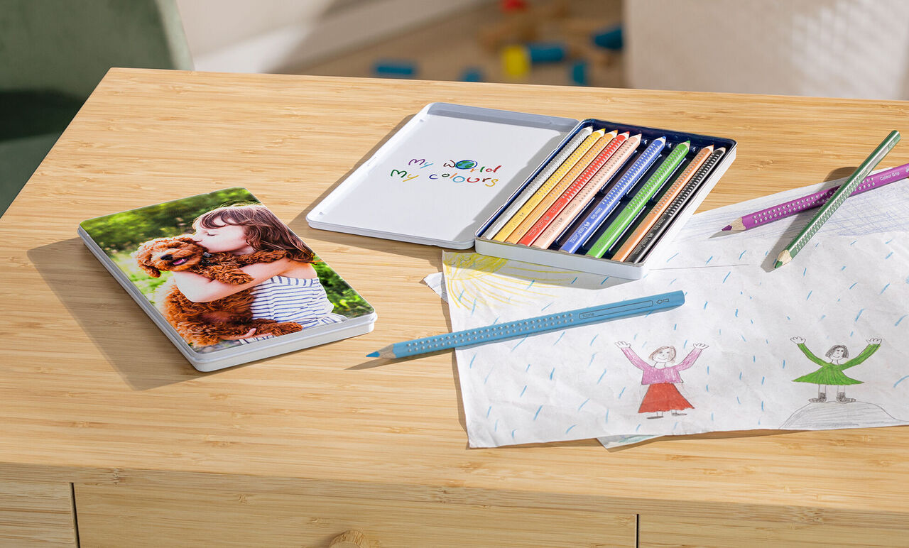 Un enfant embrasse un chien sur un livre photo. Des crayons et un bloc de dessin sont sur une table en bois.