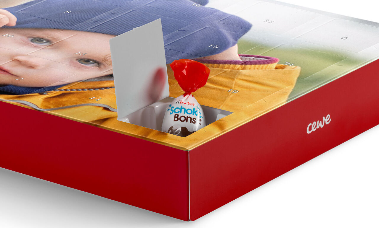 Un calendrier de l'Avent ouvert avec une image colorée et du chocolat.