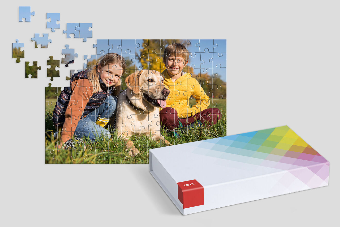 Un chien avec deux enfants assis dans un pré, des pièces de puzzle autour d'eux.