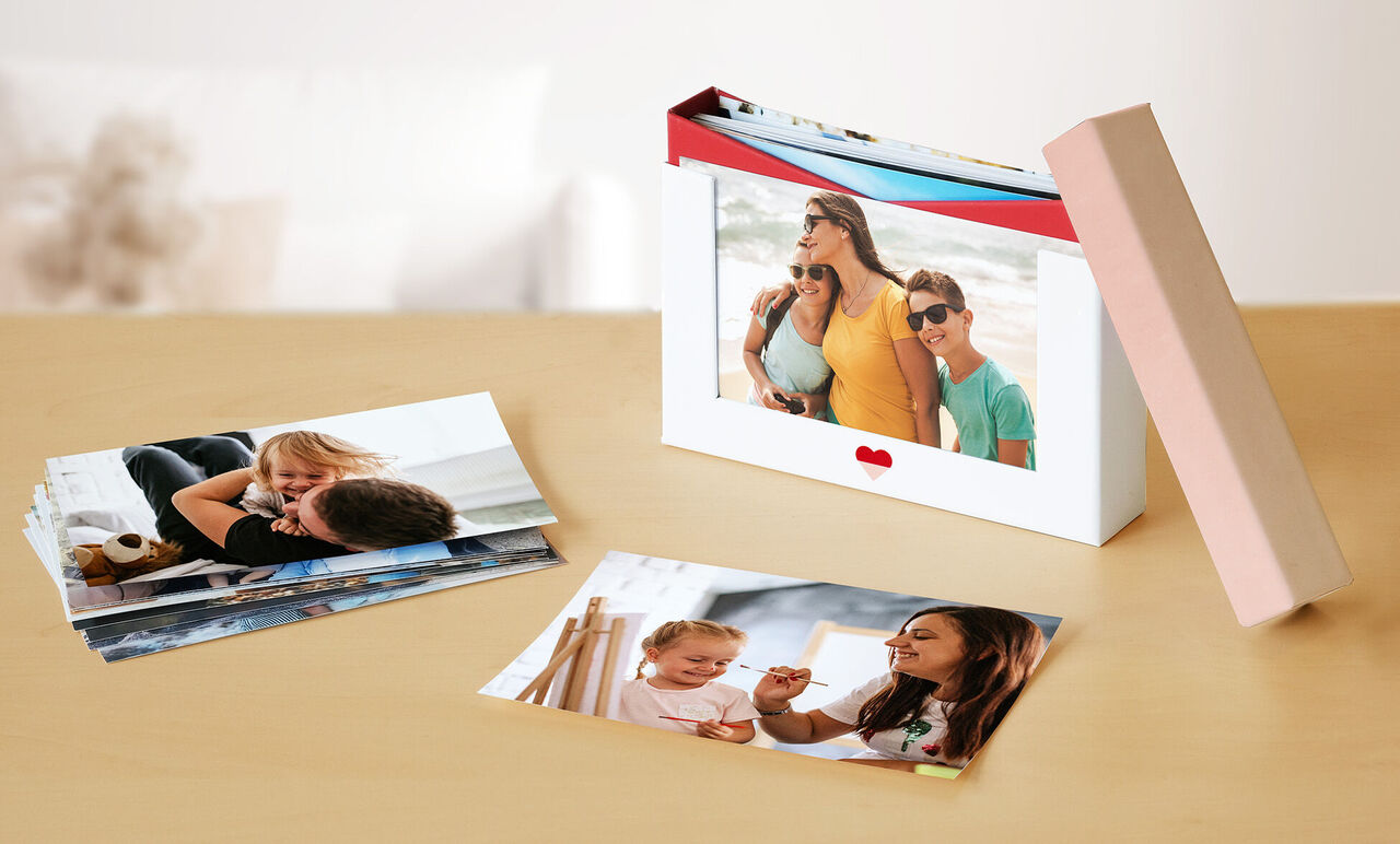 Deux cartes photo sur une table, l'une montrant une famille heureuse à la plage, l'autre une mère jouant avec son enfant.