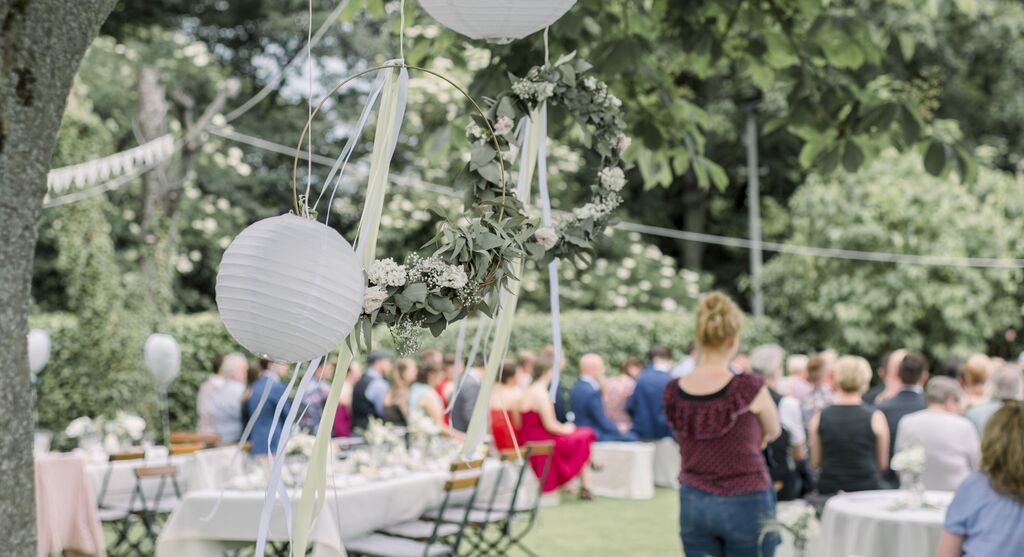 Célébration de mariage dans le jardin avec des lanternes décoratives et une couronne de fleurs