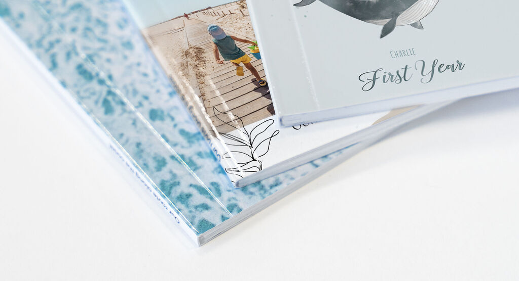 Trois albums photo empilés avec des designs colorés et des titres comme 'Première année' et 'Moments en famille'