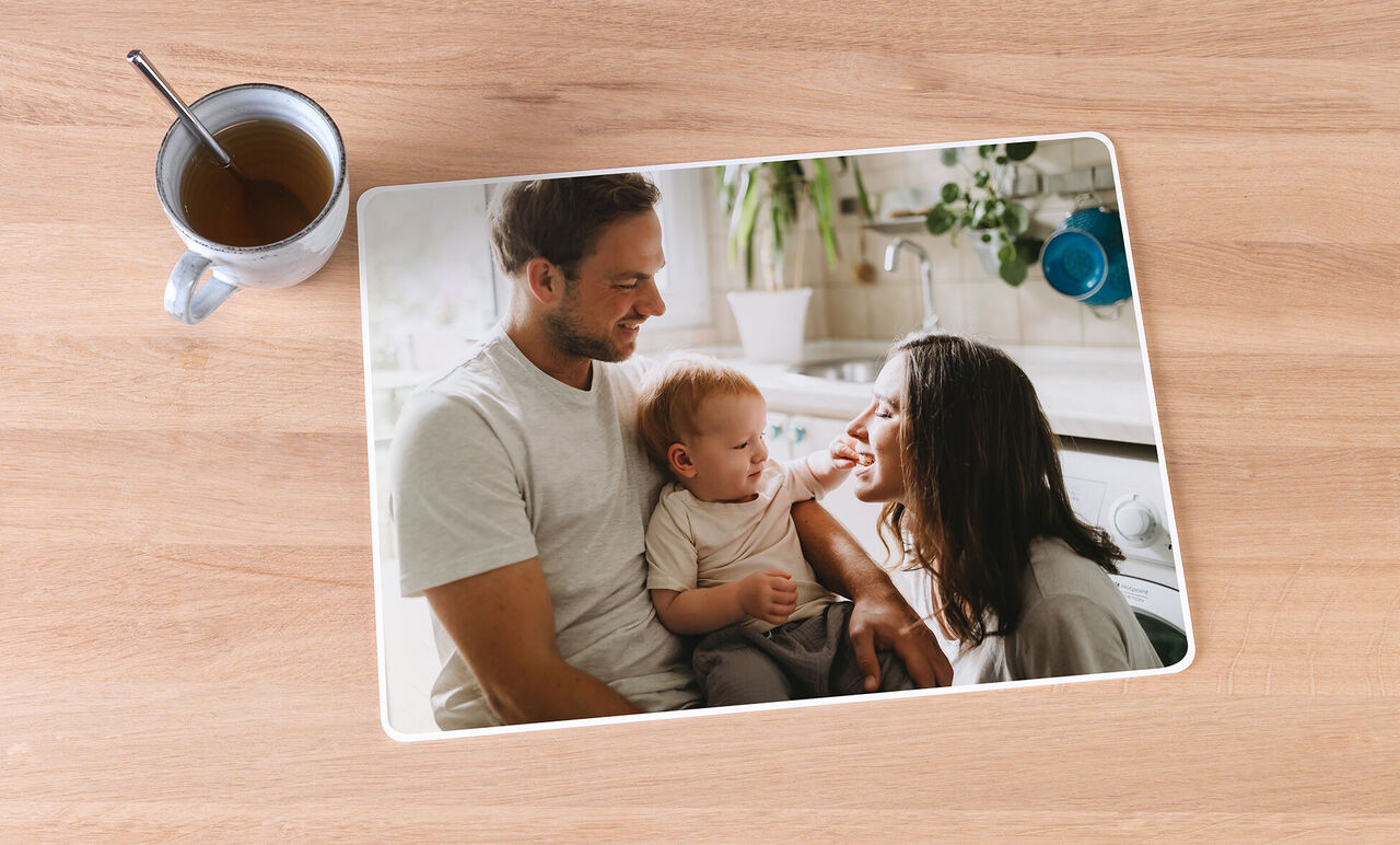 Une famille est assise à table dans la cuisine, le père tient le bébé, tandis que la mère sourit