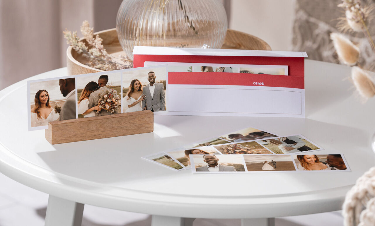 Un calendrier photo CEWE élégamment présenté sur une table avec des photos d'un mariage.