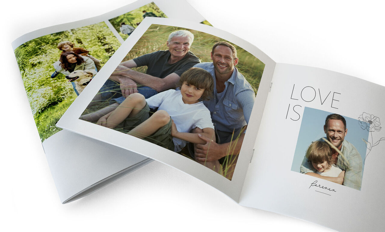 Livre photo ouvert avec des images de moments heureux, entouré par la nature.