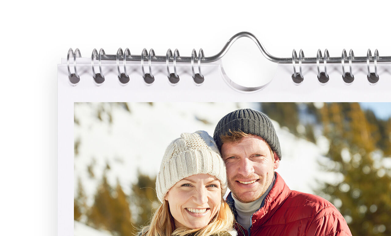 Un couple heureux pose devant un paysage de montagne enneigé dans un calendrier.