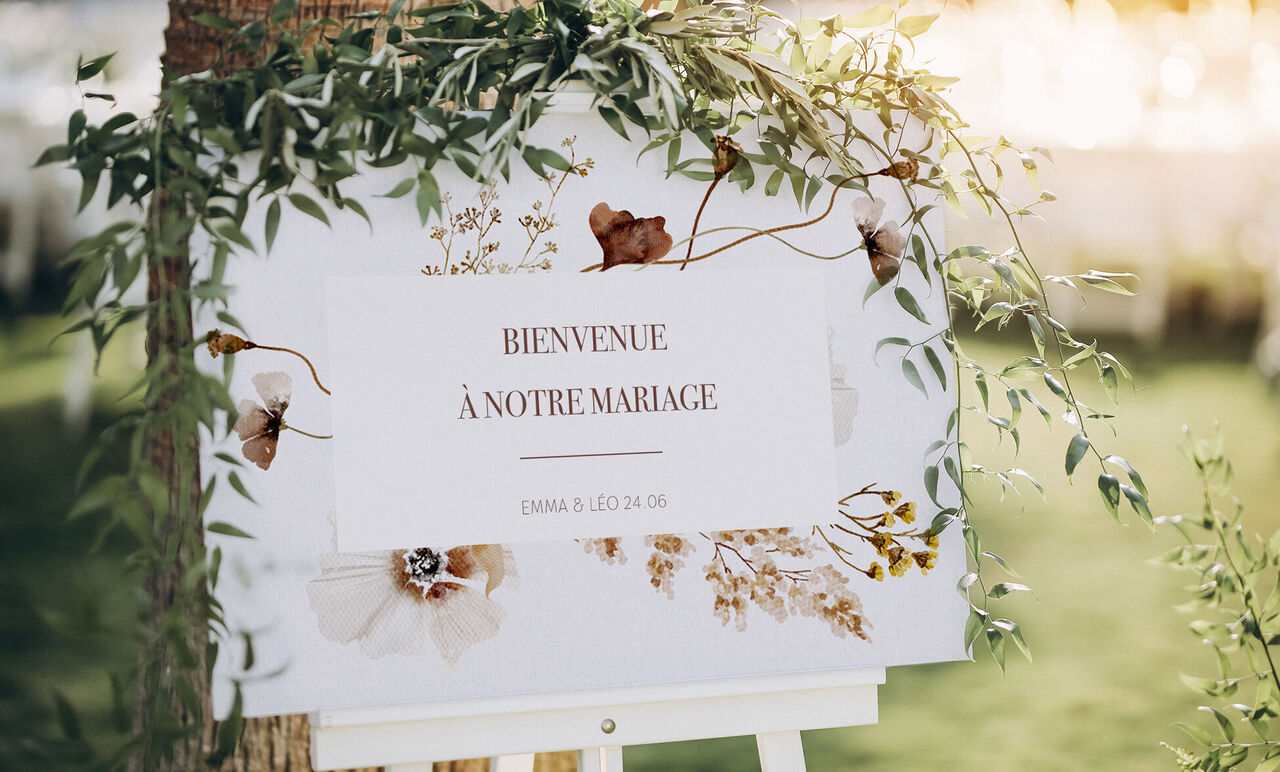 Panneau de bienvenue au mariage avec fleurs et vignes.