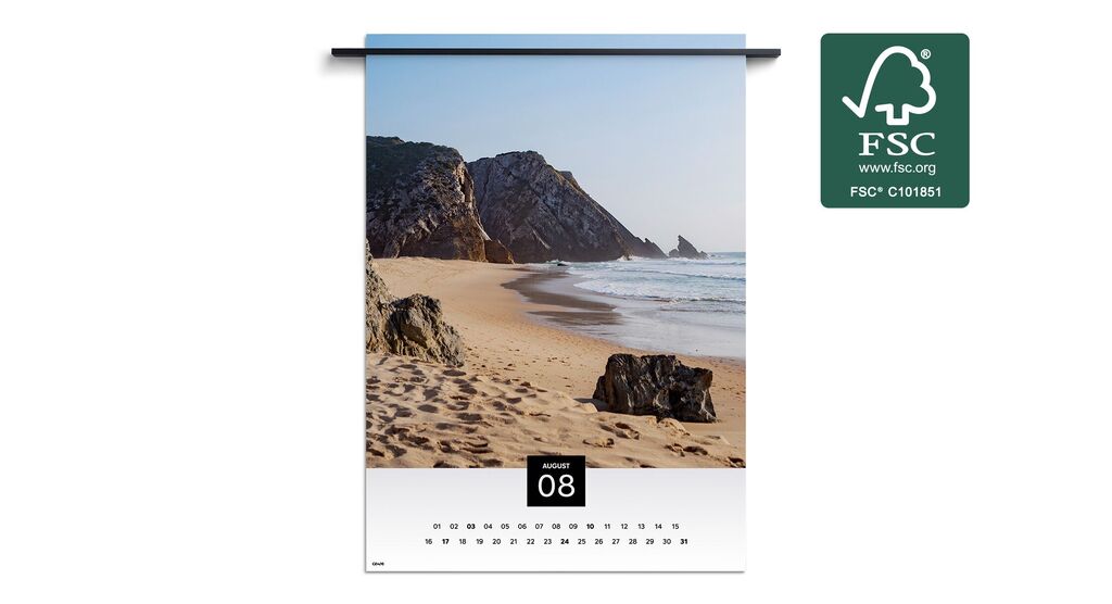 Paysage de plage avec des rochers et des vagues douces sous un ciel bleu, figurant dans un calendrier mural pour août