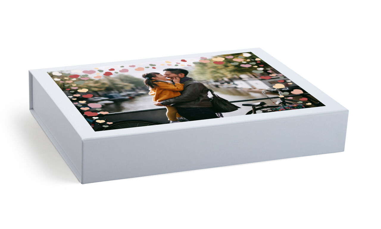 Présentation tendre d'un CEWE PHOTOBOOK sur une table, couverture montrant un couple romantique avec des fleurs.