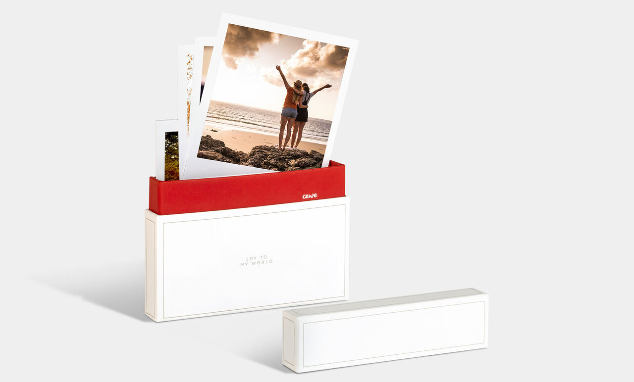 Une boîte photo CEWE avec des photos de deux personnes heureuses à la plage.