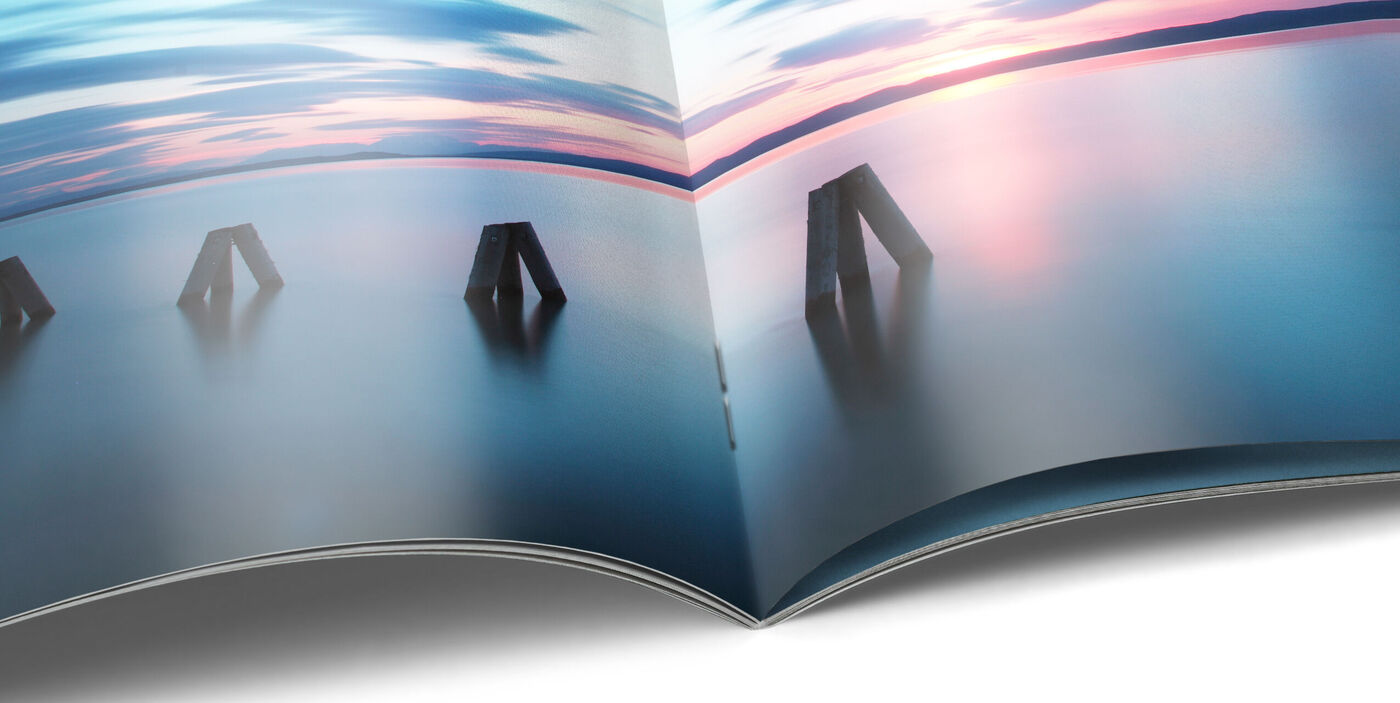 Livre photo CEWE ouvert avec paysage terrestre et marin sur une page