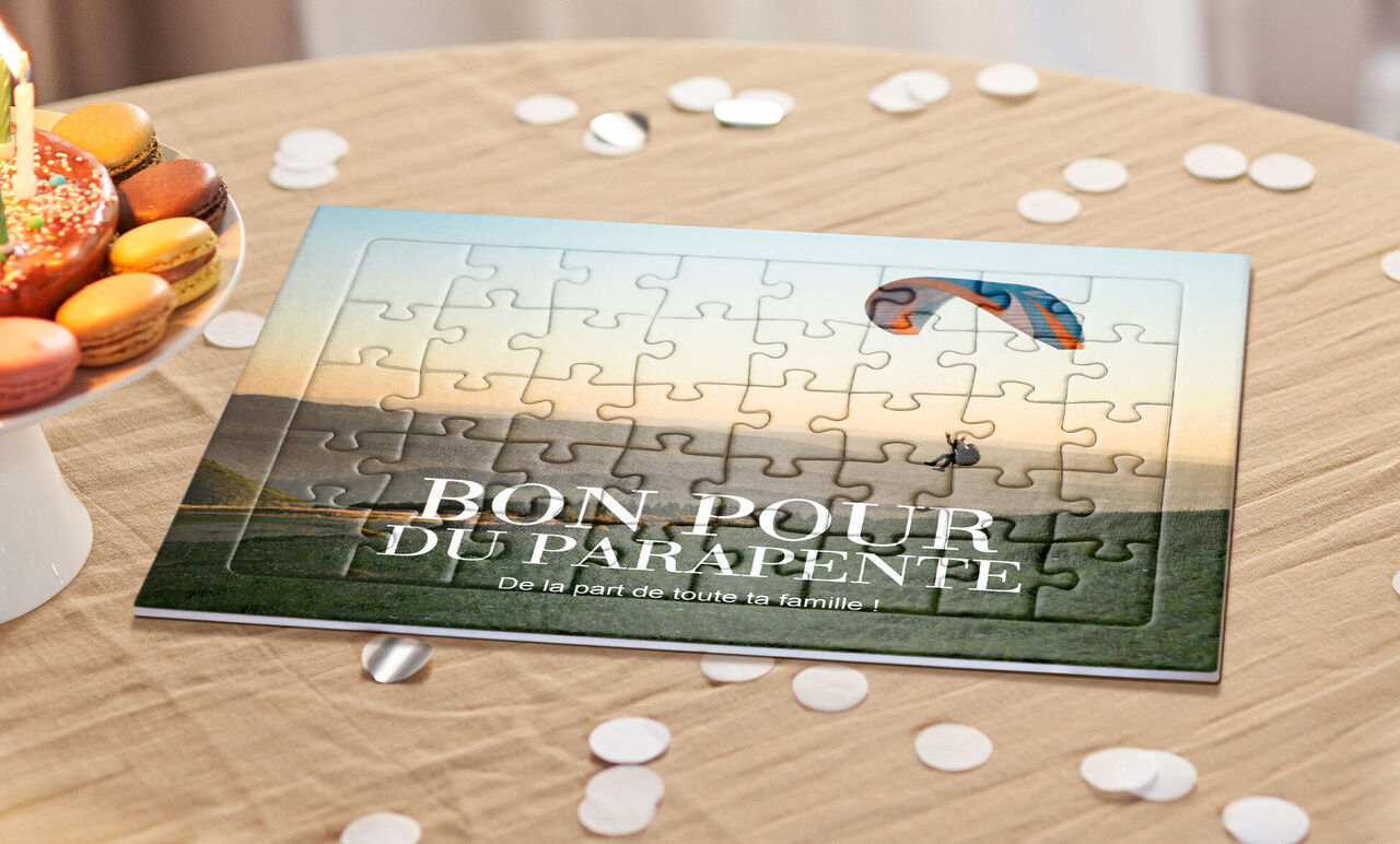 Puzzle bon pour du parapente avec un pilote en vol, posé sur une table parmi des confettis