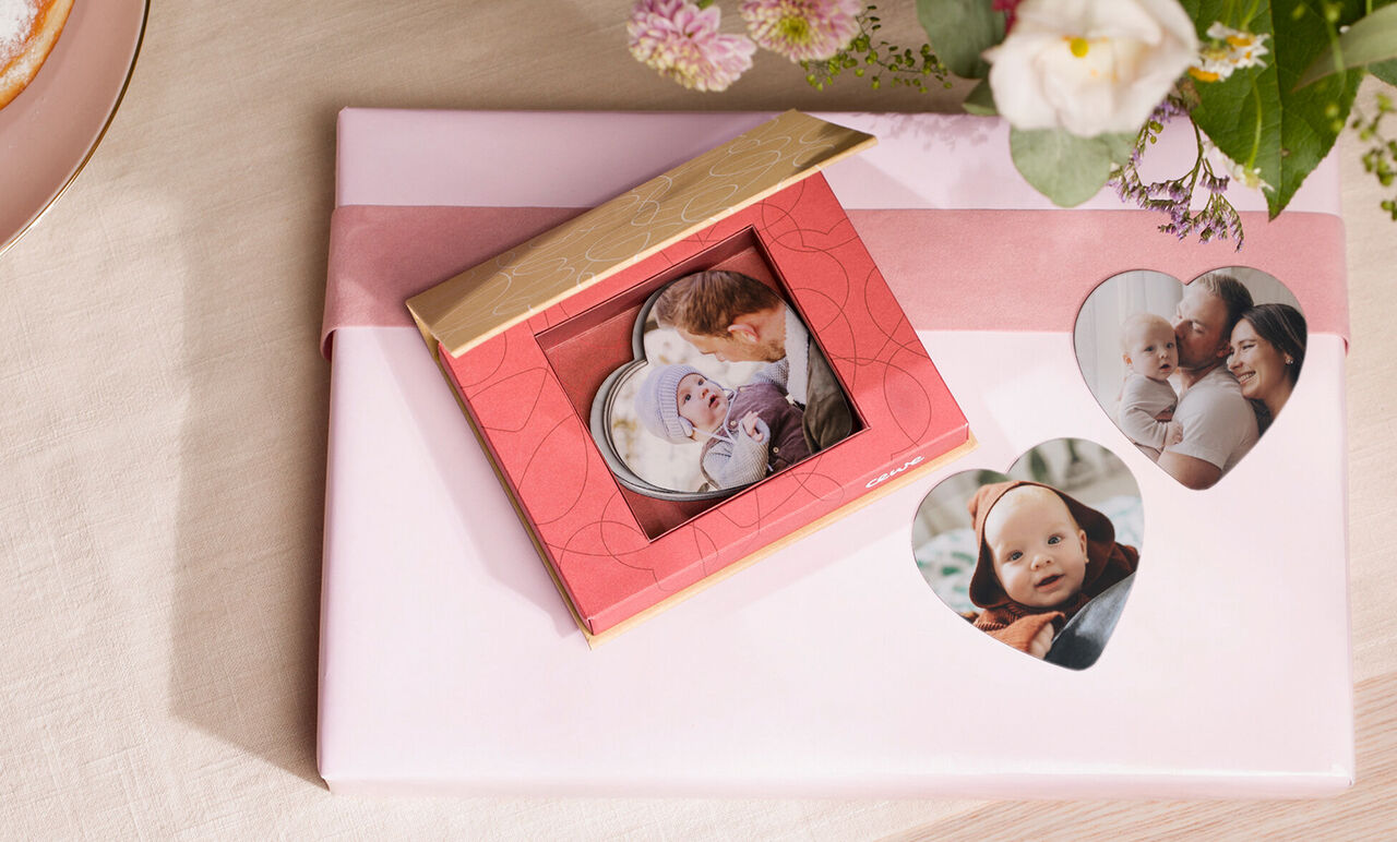 Un beau cadeau rouge avec des cartes photo présenté avec soin, entouré de fleurs.