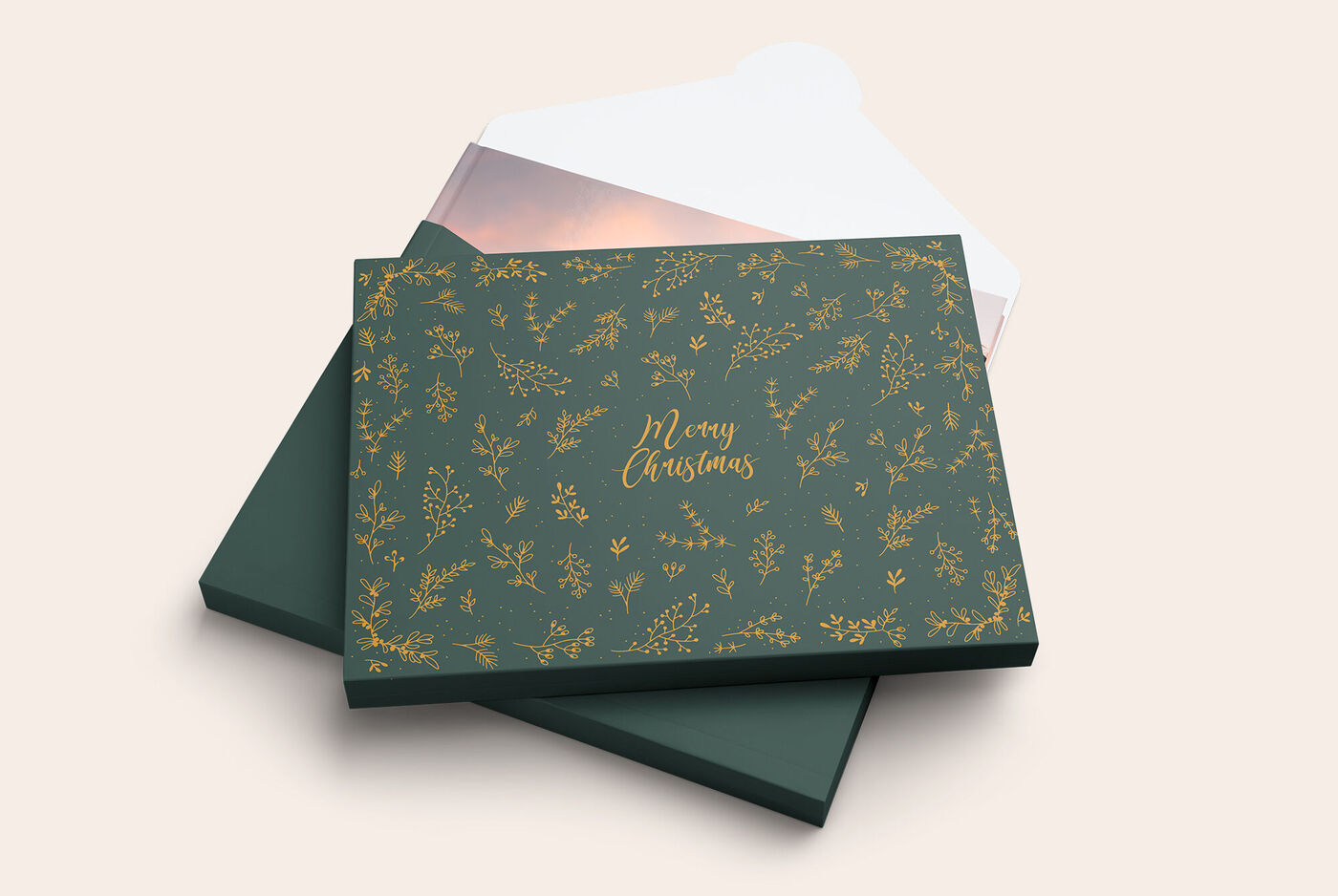Un magnifique CEWE PhotoBook avec une couverture verte élégante, décoré de motifs dorés et de l'inscription 'Joyeux Noël'.