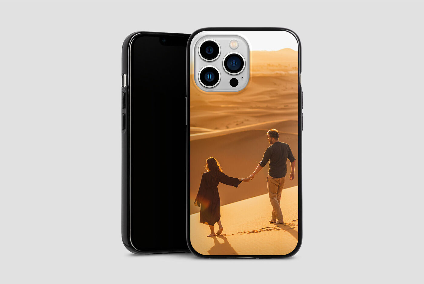 Un couple se tient la main et marche dans les dunes de sable. Les paysages de sable orange dégagent chaleur et joie.