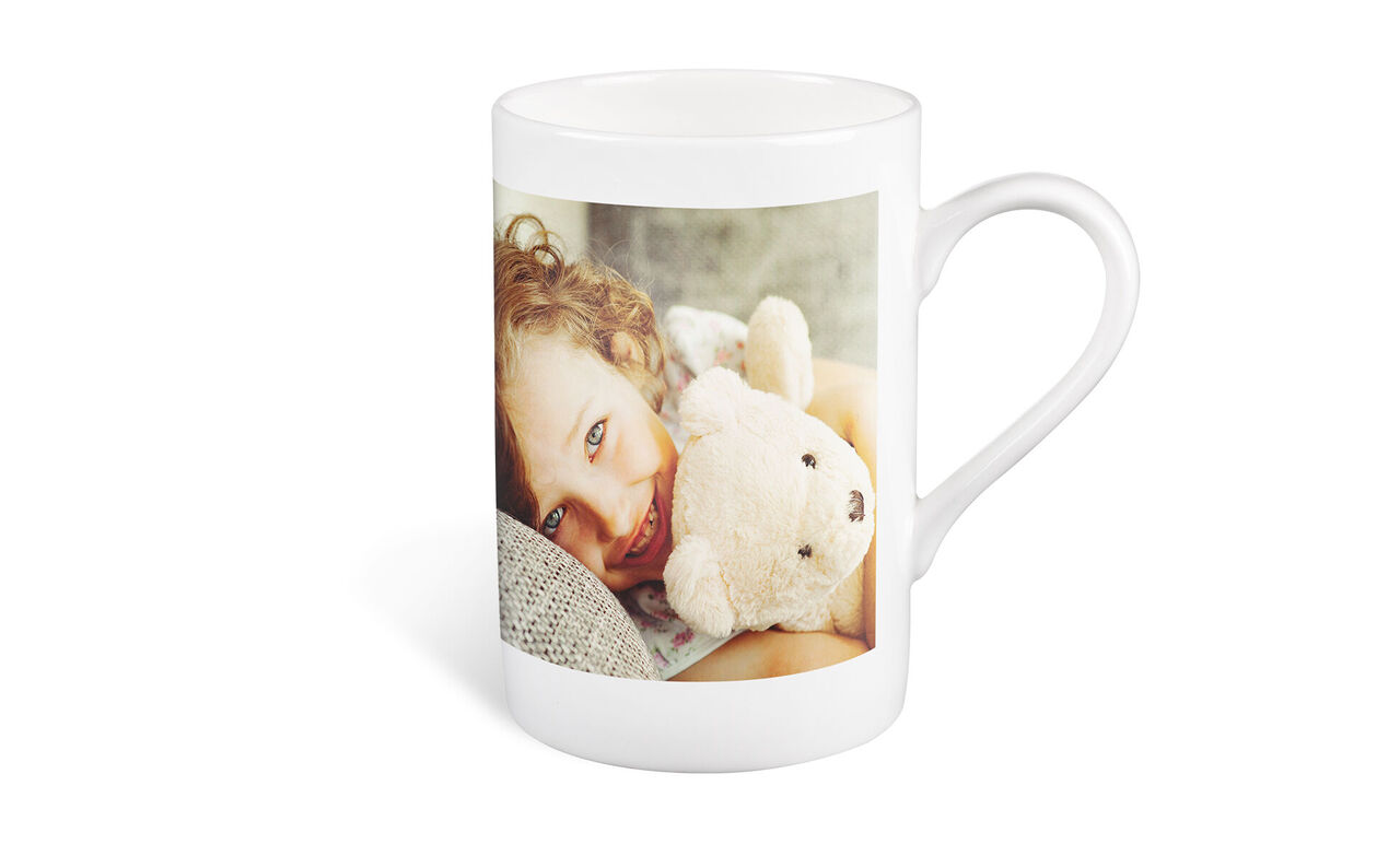 Une tasse avec une photo et un ours en peluche.