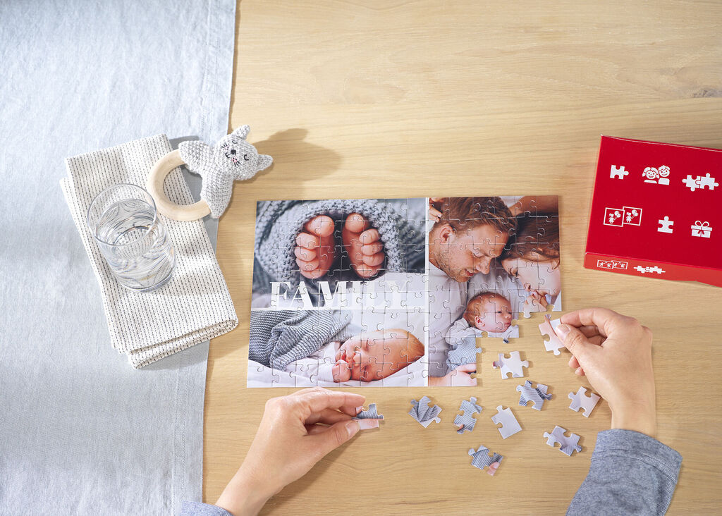 Un puzzle affectueux montre des petits pieds et un sourire. C'est un souvenir créatif. Entouré d'un verre d'eau et d'une serviette.