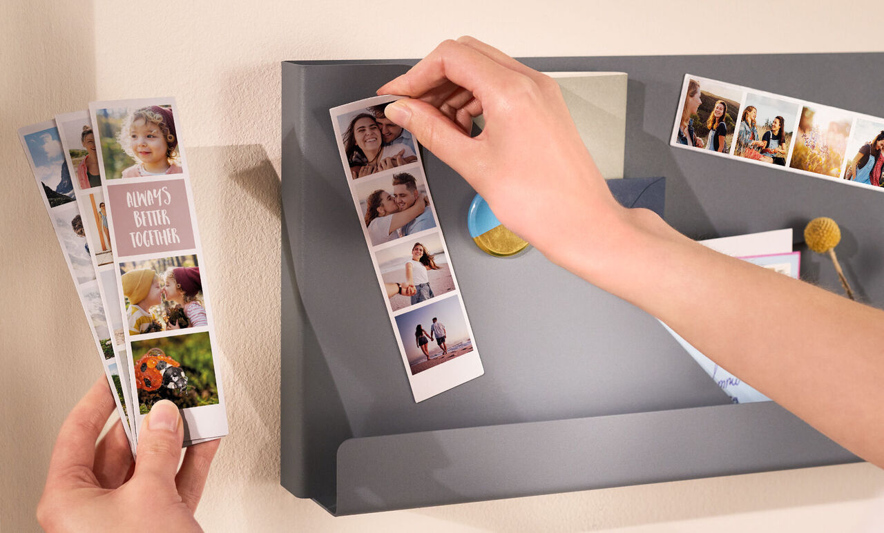 Une personne tire une carte photo d'un casier mural gris avec d'autres souvenirs.