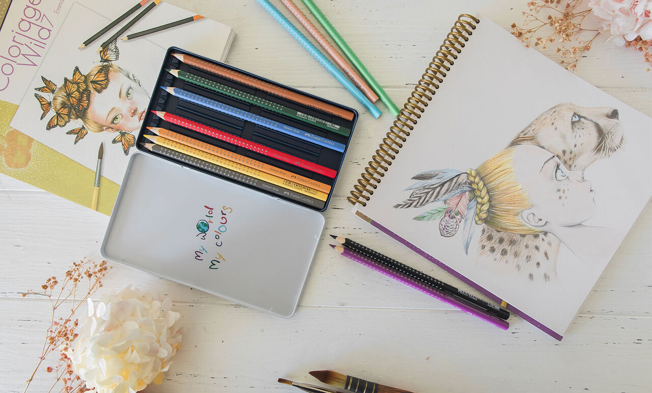 Set de crayons de couleur avec carnet de dessin ouvert sur un portrait au crayon