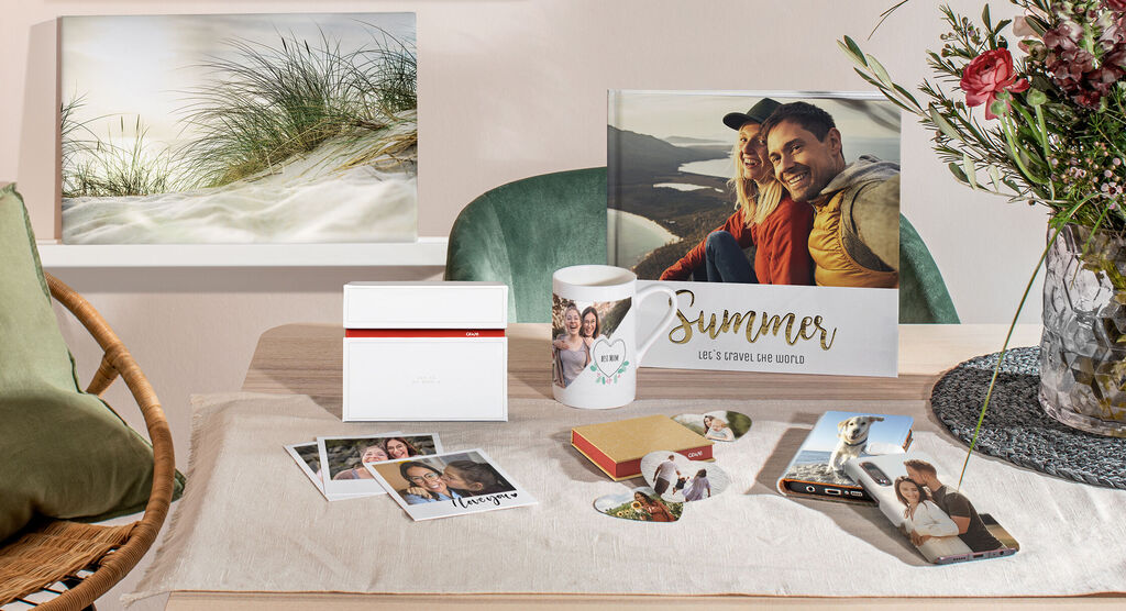 Une arrangement créatif avec des produits photo sur une table, dont un livre photo, des tasses et des photos d'été