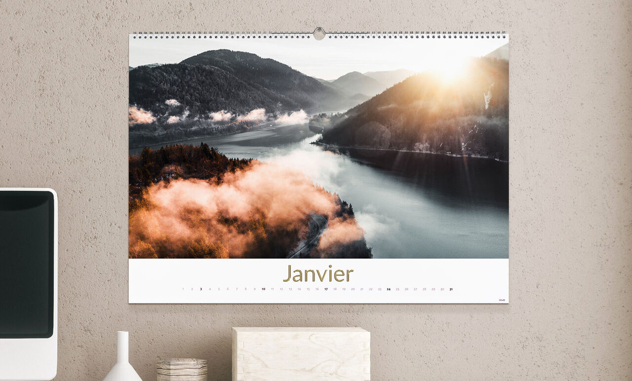 Calendrier suspendu avec une vue panoramique sur des montagnes et des rivières au crépuscule, bien éclairé.