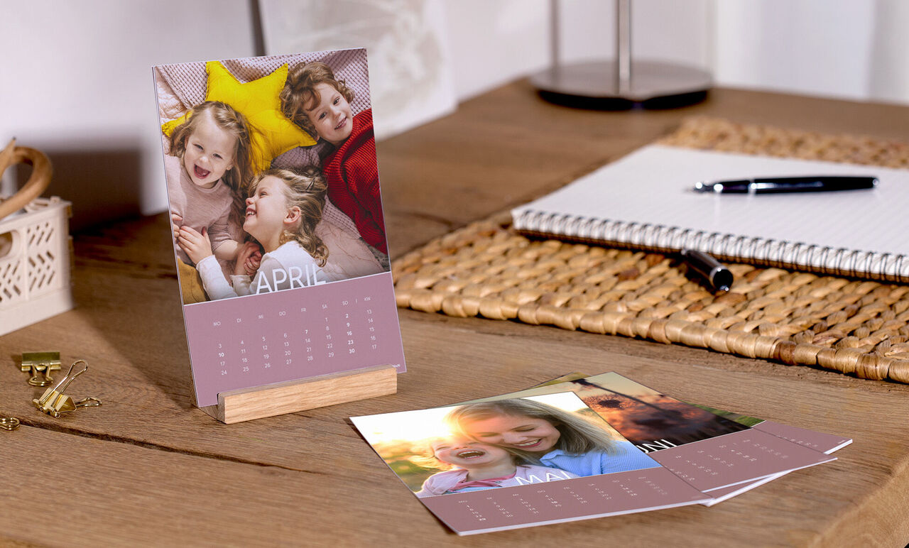 Une table colorée avec un calendrier photo CEWE, des images de moments heureux et de doux souvenirs.