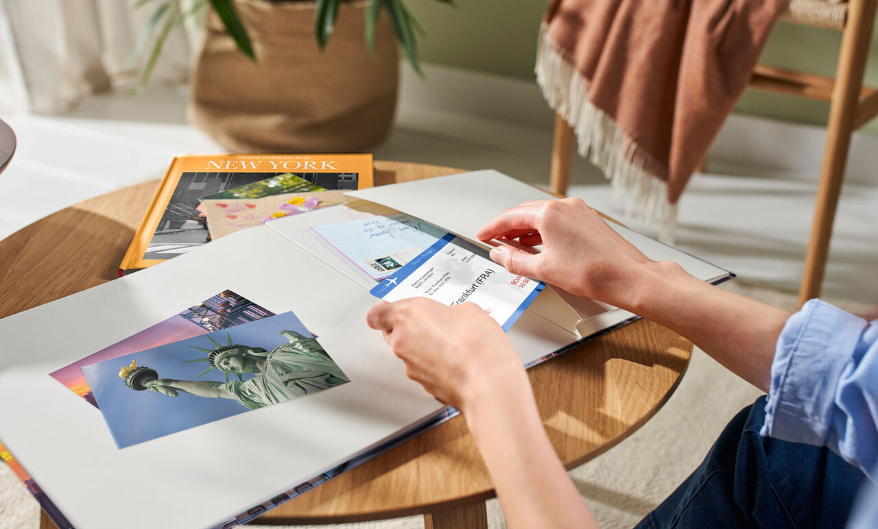 Des mains feuillettent un album photo ouvert avec des souvenirs de New York.