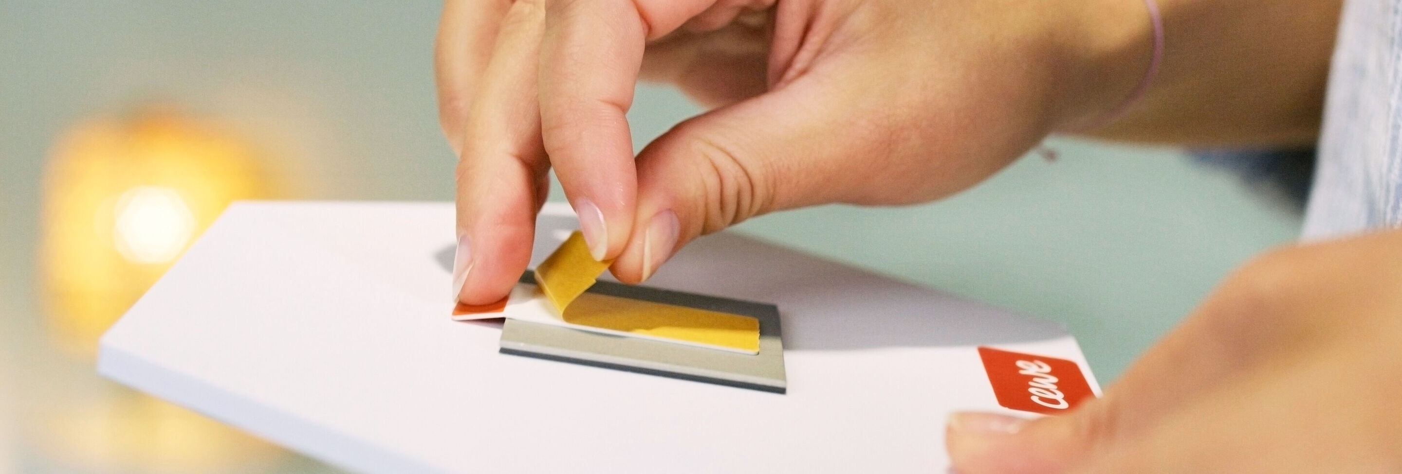 Une main retire un film jaune d'une carte de vœux CEWE